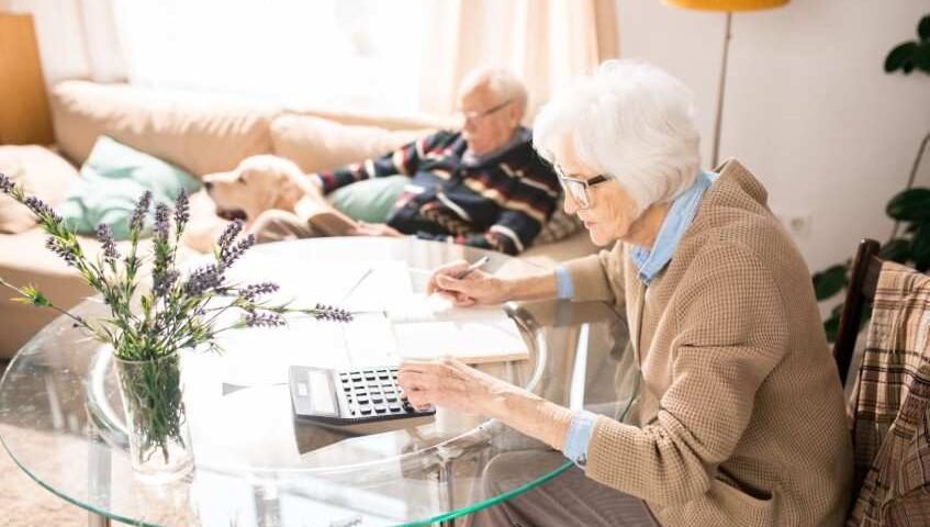 Senior woman managing her finances in a cozy living room, demonstrating the independence and financial management opportunities available in senior living communities.