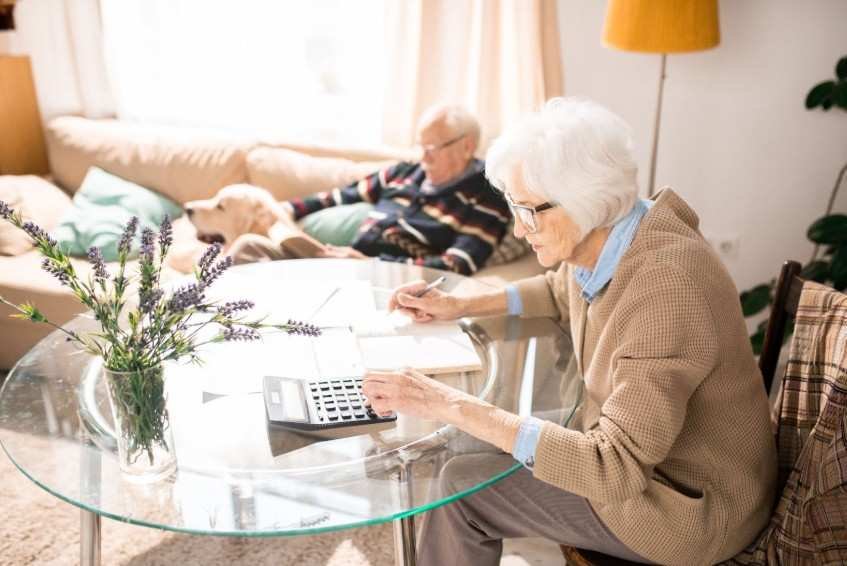 Senior woman managing her finances in a cozy living room, demonstrating the independence and financial management opportunities available in senior living communities.